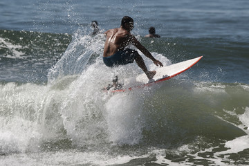 Junger männlicher Surfer reitet auf dem Wellenkamm