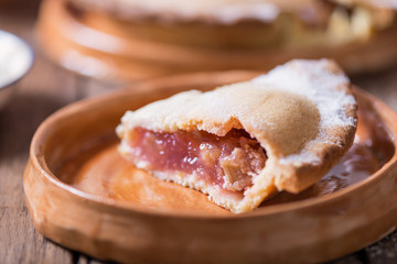 Piece of fresh rhubarb and strawberry pie with cream nearby