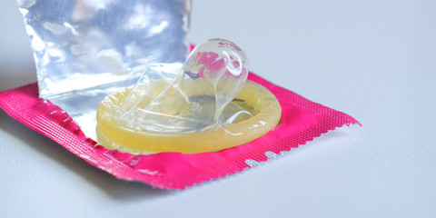 Close up of a yellow condom on white background