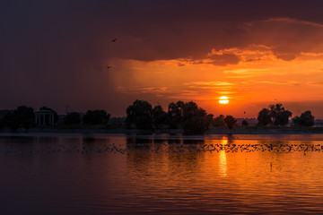 Fototapeta premium A Dark Orange Lake Sunset and a Lot of Silhouettes