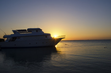 Obraz premium sunset over the sea with a yacht