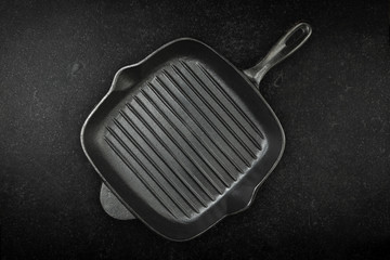 Empty black cast iron frying pan on marble work surface.