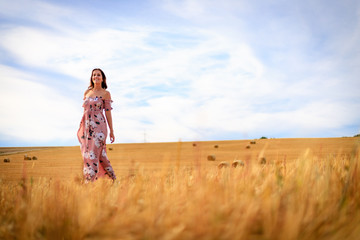 Young woman is walking through a stubble field