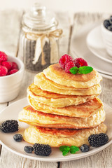 Pancakes with blueberries, honey and raspberry on a wooden background