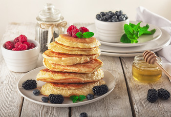 Pancakes with blueberries, honey and raspberry on a wooden background