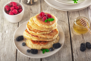 Pancakes with blueberries, honey and raspberry on a wooden background