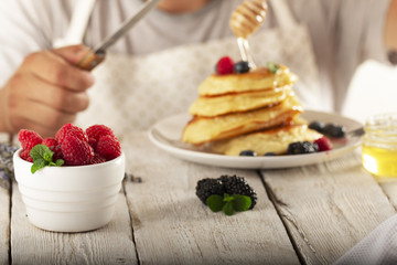 young man eating pancakes with fruit