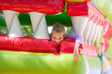 The girl lies in the mouth of the dragon on a soft inflatable trampoline