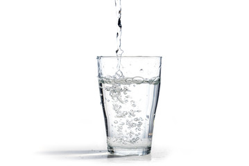 Wasser wird in ein Trinkglas gegossen, isoliert auf weißem Hintergrund mit Kopienraum