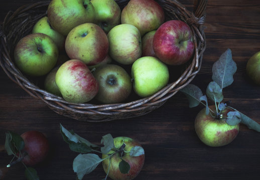 Red and green apples in basket on wooden table