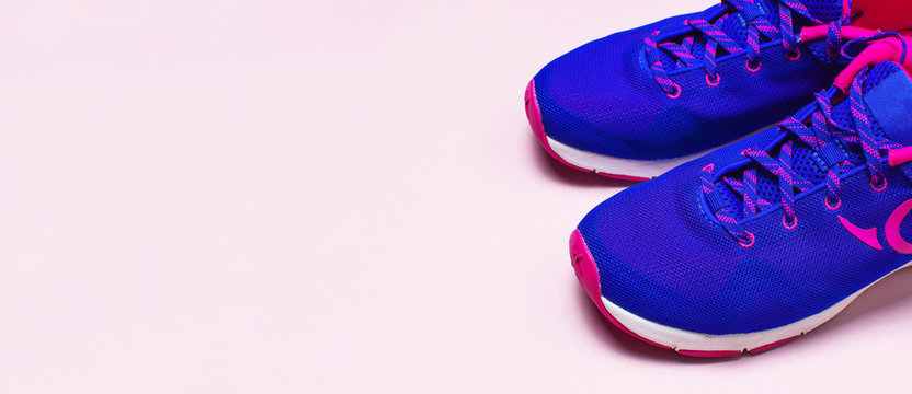 Ultra blue violet pink female sneakers on pastel pink background flat lay top view with copy space. Sports shoes, fitness, concept of healthy lifestile, everyday training.