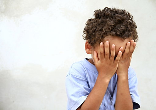 poverty boy crying with hands over face stock photo