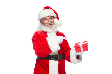 Christmas. Smiling Santa Claus in white gloves is holding a gift red box with a bow. Pointing at the gift. Isolated on white background.