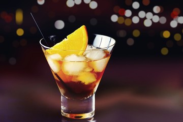 Whiskey cocktail glass with lights background. Alcoholic cocktail isolated on black