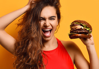 Woman hold big barbecue burger sandwich with hungry mouth happy screaming laughing on yellow...