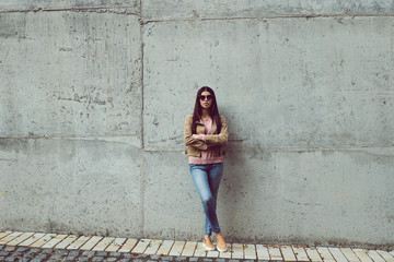 Fototapeta na wymiar Casual and calm. Full length of beautiful young woman looking at camera while standing against concrete background outdoors 