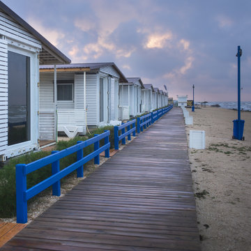 view to wooden pathway and resort buildings on the beach in sunset time with clouds