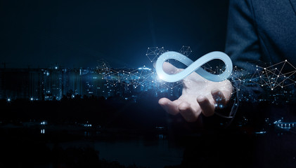 Businesswoman shows sign of infinity on the background of the city.