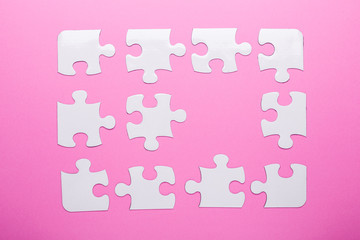 White puzzle on pink background. Top view