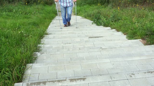 Disabled man with crutches walking on staircase
