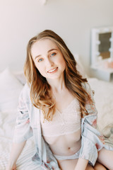 Naklejka premium Girl in the early morning in bed and Bathrobe, wakes up and getting ready to work. Productive day. Smiles and laughs. Lying in bed, catching the sunrise. Happy morning in the bedroom.