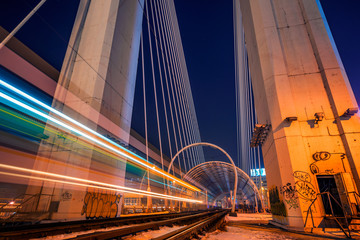 Night shot long exposure with a tram passing by and leaving light streaks and two rails used by...
