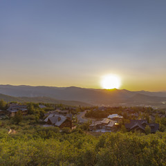 Sun shining on valley with homes in hills square