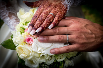 Les jeunes mariés présentent leurs alliances. Gros plan sur les mains devant le bouquet de fleurs de la mariée