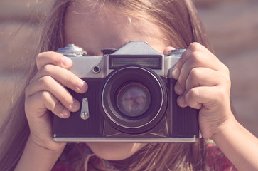 The girl photographs an old Soviet camera in brown tonting.