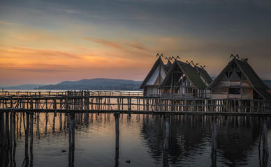 Fototapeta na wymiar Antique wooden huts on water at sunset