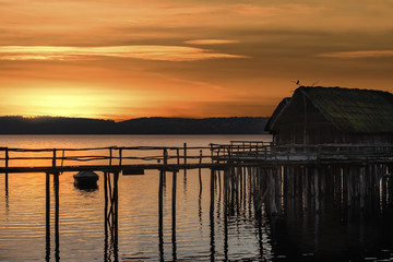Cabin on pillars over lake at sunset