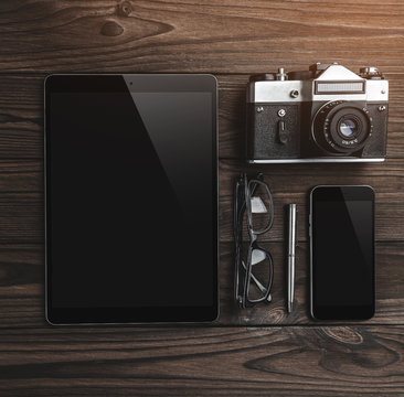 Work space for photographer. Flat lay of digital tablet, camera, phone, glasses, pencil on wooden table