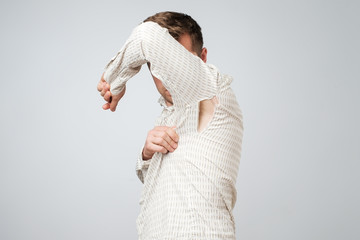 A young handsome man accidentally tore his shirt on his armpit.