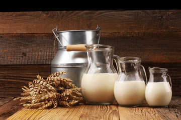 A jug of milk and glass of milk on a wooden table