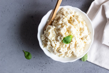 Organic ricotta cheese in white bowl with corn salad and milk jug.