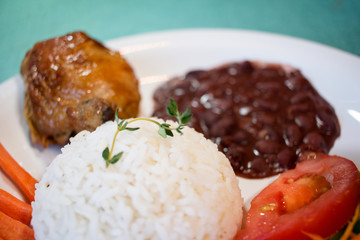 Brasileirinho - Brazilian made typical dish of beans with rice with salad of lettuce, tomato and carrot and roast chicken.