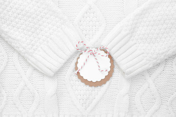 Obraz na płótnie Canvas Festive white knitted winter sweater with a label for congratulations. Winter holidays. Horizontal