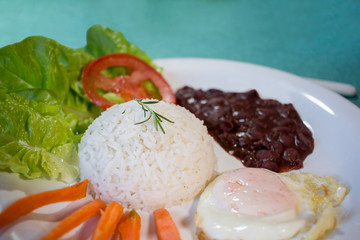  Brasileirinho - Brazilian made typical dish of beans with rice with salad of lettuce, tomato and carrot and fried egg.