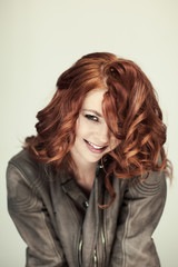 Obraz premium Portrait of a beautiful woman with perfect styled red curly hairand natural make up, cool, casual easy look in leather jacket, coat 