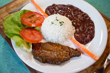 Brasileirinho - Brazilian made typical dish of beans with rice with salad of lettuce, tomato and carrot and steak.