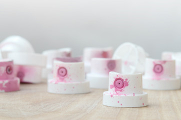 Several plastic nozzles from a paint sprayer that lie on a wooden surface against a gray wall...