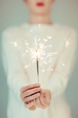 Beautiful woman hands holding sparkler lights, cozy, bright winter sweater, can be used as...