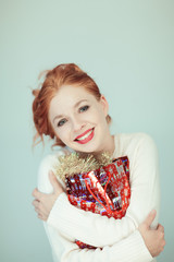 Beautiful woman with red curly hair holds a christmas gift in her hands, can be used as background 