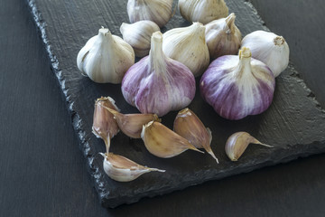 Garlic on a black serving board.