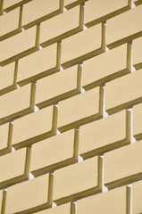 Decorative concrete wall with a relief similar to a large brick masonry painted in bright yellow...
