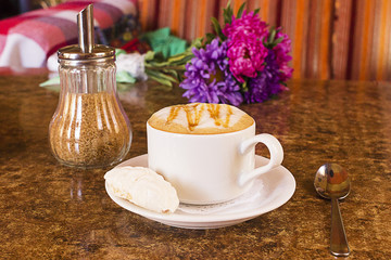 Cup of hot cocoa or Cappuccino or latte coffee with marshmallow and flowers on a table