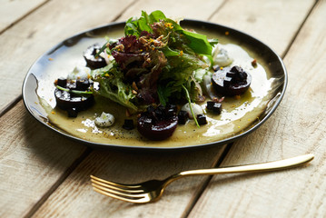 Salad with roasted beetroot, spinach, soft goat cheese on wooden table, top view, copy space. 