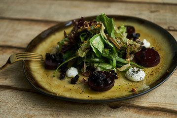 Salad with roasted beetroot, spinach, soft goat cheese on wooden table, top view, copy space. 