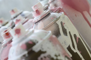 A lot of dirty and used aerosol cans of bright pink paint. Macro photograph with shallow depth of...