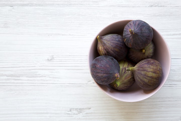 Fresh figs in a pink bowl on a white wooden background. Top view, overhead, from above. Space for text.